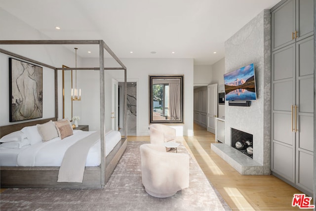 bedroom with a large fireplace and light wood-type flooring