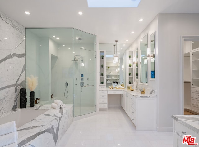 bathroom featuring vanity, shower with separate bathtub, and a skylight