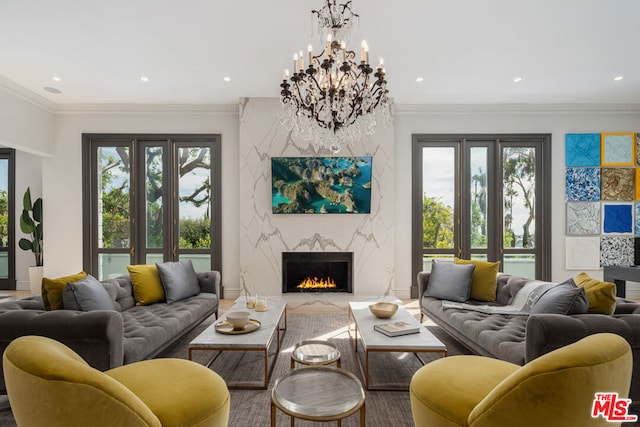 living room featuring ornamental molding, a notable chandelier, a fireplace, and a healthy amount of sunlight