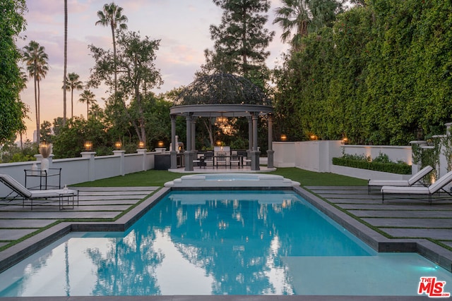 pool at dusk with a gazebo, a yard, and a patio