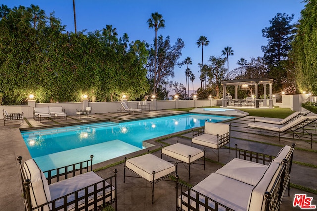 pool at dusk featuring a gazebo and a patio area