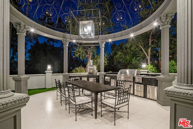 patio at night featuring an outdoor kitchen and grilling area