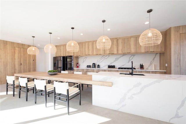 kitchen featuring decorative backsplash, sink, light brown cabinets, stainless steel fridge with ice dispenser, and hanging light fixtures