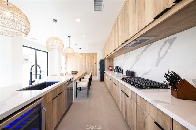 kitchen featuring appliances with stainless steel finishes, tasteful backsplash, beverage cooler, sink, and pendant lighting