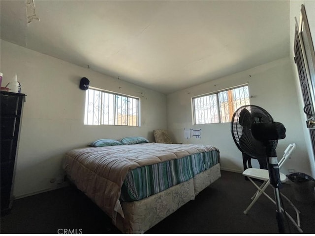 bedroom with dark colored carpet and multiple windows