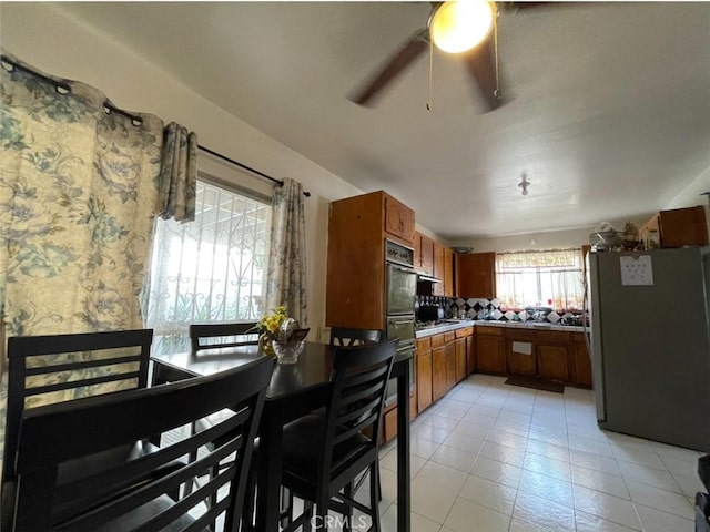 kitchen with tasteful backsplash, stainless steel refrigerator, ceiling fan, and light tile patterned floors