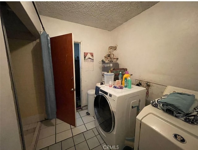 laundry area with washer and dryer, light tile patterned floors, and a textured ceiling