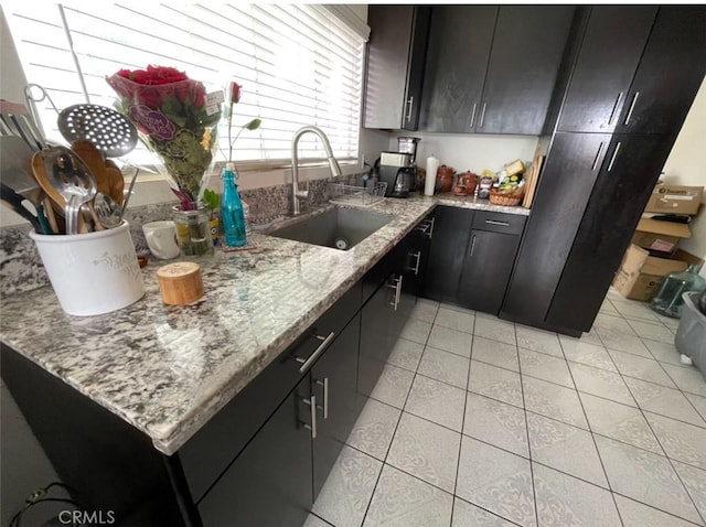 kitchen with light stone countertops, light tile patterned floors, and sink