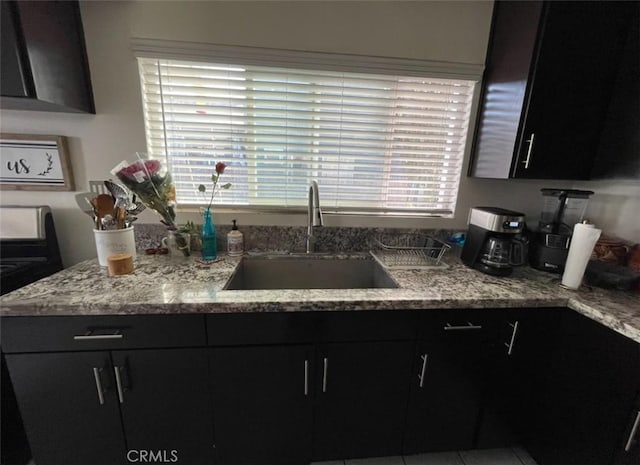 kitchen with light stone countertops, electric range, a wealth of natural light, and sink