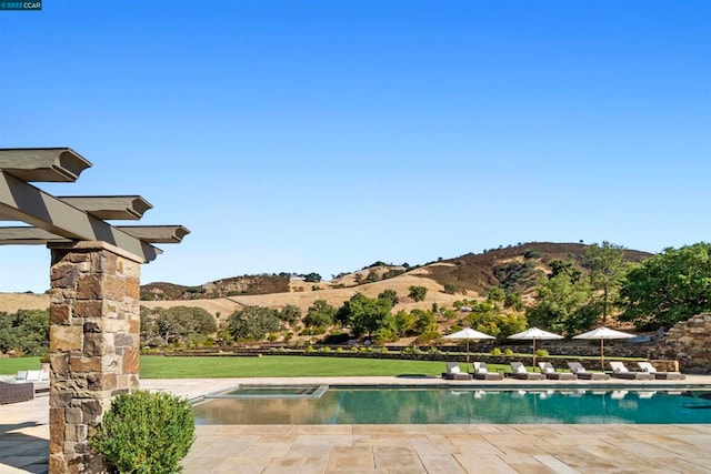 view of pool featuring a lawn, a patio, and a mountain view