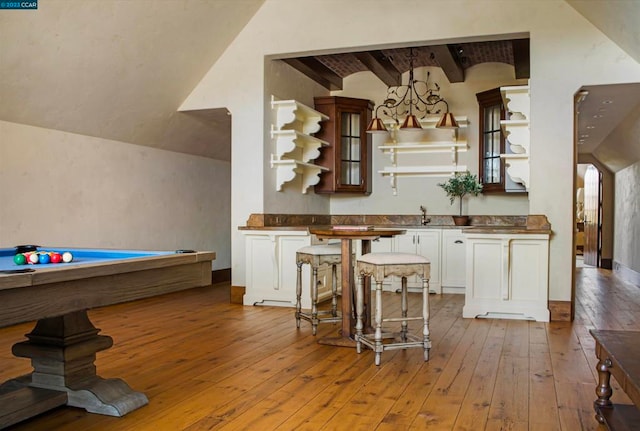 kitchen with vaulted ceiling with beams, billiards, light hardwood / wood-style floors, white cabinets, and pendant lighting