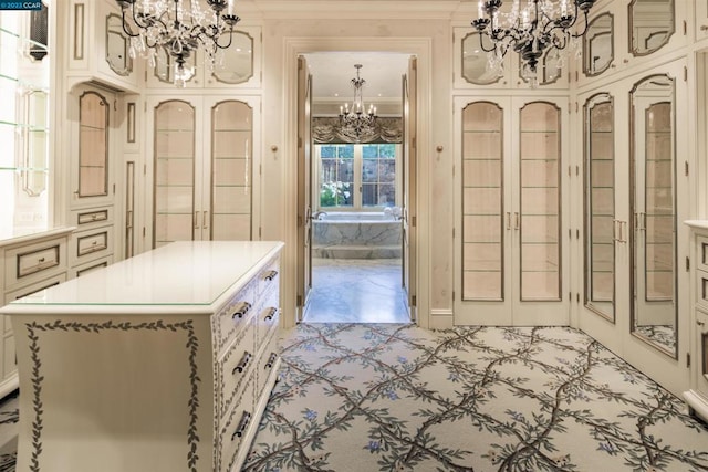 kitchen with a notable chandelier, a kitchen island, decorative light fixtures, white cabinetry, and crown molding