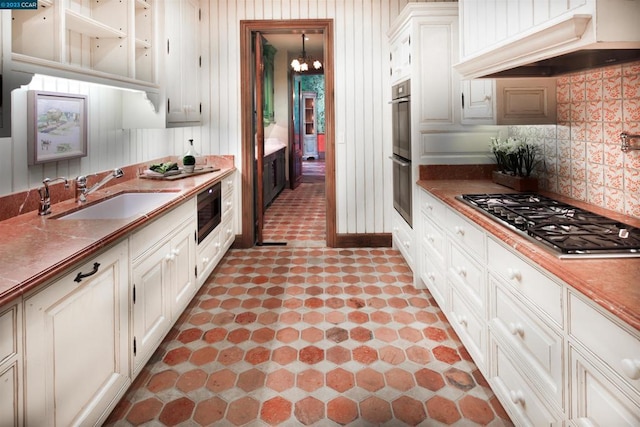 kitchen with gas stovetop, light tile flooring, a notable chandelier, sink, and custom range hood