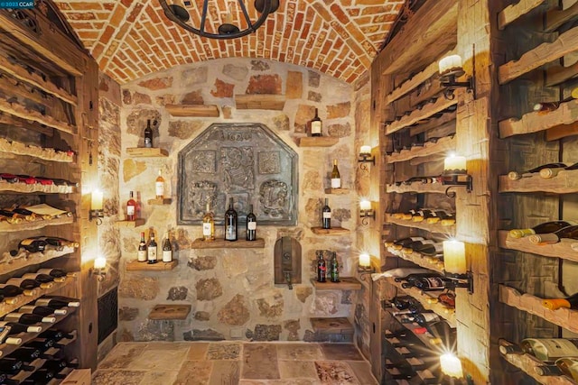 wine room featuring brick ceiling, an inviting chandelier, and vaulted ceiling