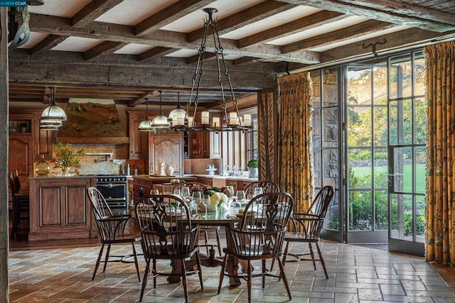 dining room featuring beam ceiling, a healthy amount of sunlight, and a chandelier