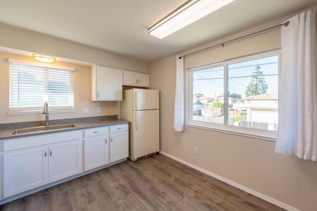 kitchen with dark wood-type flooring, a healthy amount of sunlight, sink, and white fridge