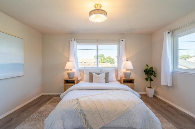 bedroom with multiple windows and dark wood-type flooring