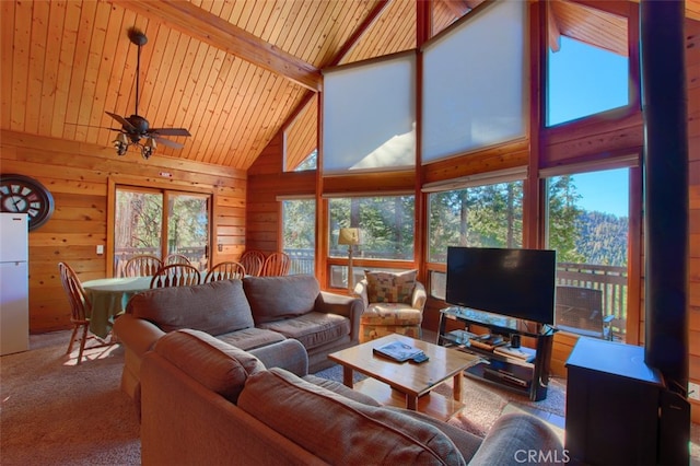 carpeted living room with wood ceiling, ceiling fan, high vaulted ceiling, beamed ceiling, and wood walls