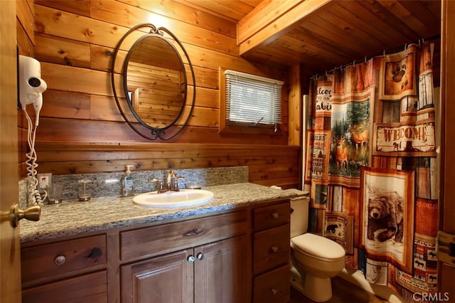 bathroom with beam ceiling, wood walls, toilet, vanity, and wood ceiling