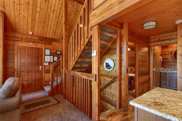 stairs with hardwood / wood-style flooring, wooden ceiling, and wooden walls