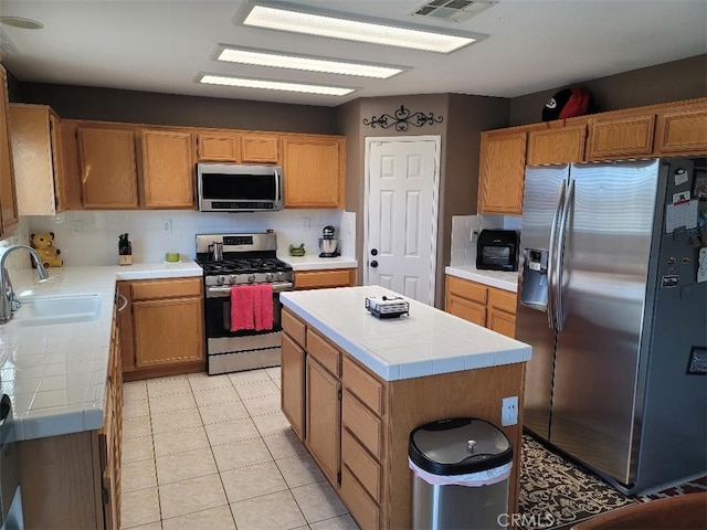 kitchen with tasteful backsplash, stainless steel appliances, sink, a center island, and tile counters