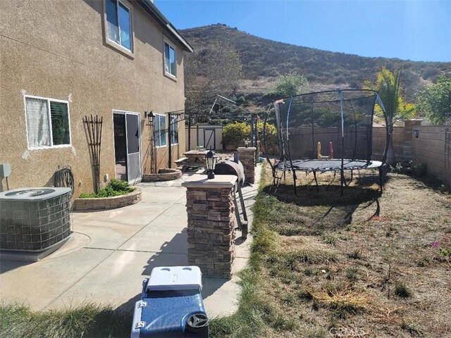 view of yard featuring a patio area, a mountain view, central AC unit, and a trampoline