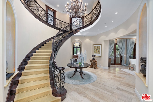 entryway featuring french doors, a towering ceiling, an inviting chandelier, and a wealth of natural light