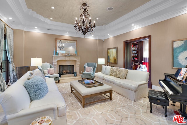 living room featuring a tray ceiling, a premium fireplace, ornamental molding, and an inviting chandelier