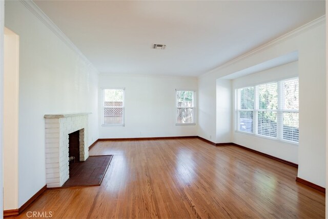 unfurnished living room featuring a healthy amount of sunlight, ornamental molding, and a brick fireplace