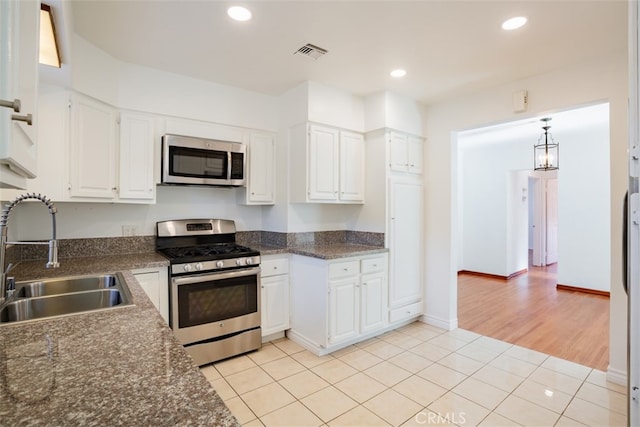 kitchen featuring sink, white cabinets, light tile patterned floors, and appliances with stainless steel finishes