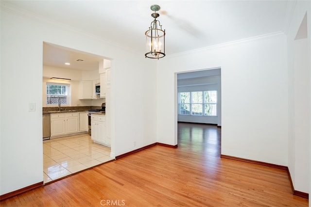 unfurnished dining area featuring crown molding, sink, a notable chandelier, and light hardwood / wood-style flooring