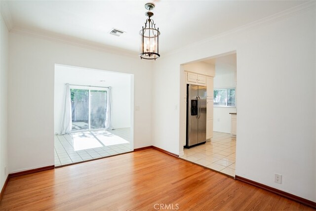 unfurnished room with a chandelier, crown molding, and light hardwood / wood-style floors