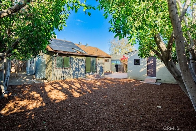 back of house with solar panels and central AC