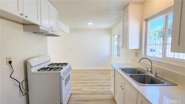 2325 Angela St, Pomona, CA 91766 - kitchen featuring white gas stove, white cabinetry, sink, and light hardwood / wood-style flooring