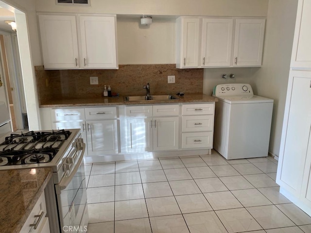 kitchen with backsplash, gas range gas stove, sink, white cabinets, and washer / dryer