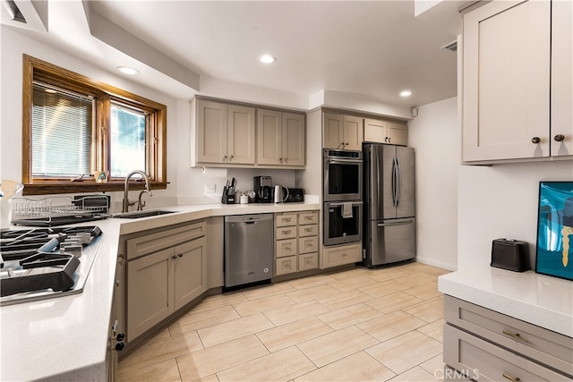 kitchen featuring stainless steel appliances, sink, and gray cabinetry