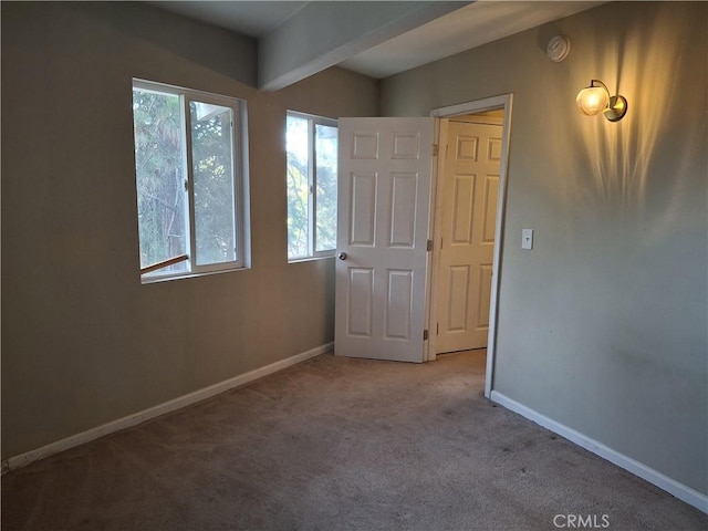 unfurnished bedroom with beamed ceiling and light colored carpet