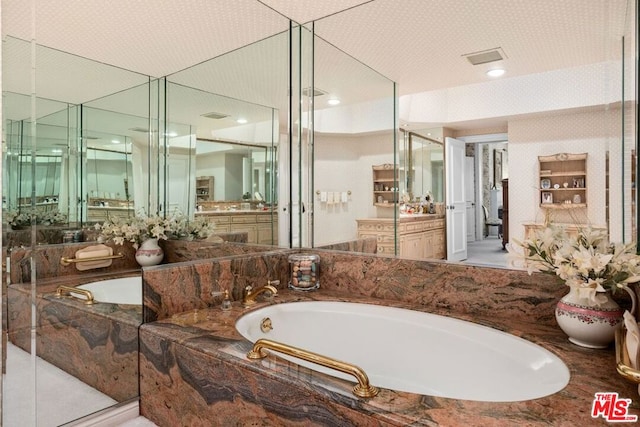 bathroom with tiled bath and vanity