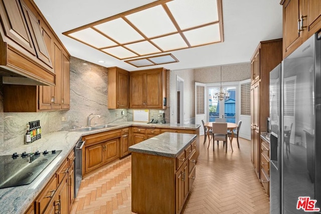 kitchen featuring appliances with stainless steel finishes, a kitchen island, an inviting chandelier, decorative light fixtures, and sink