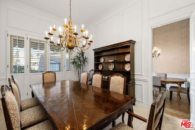 dining space with ornamental molding, a chandelier, and light parquet flooring