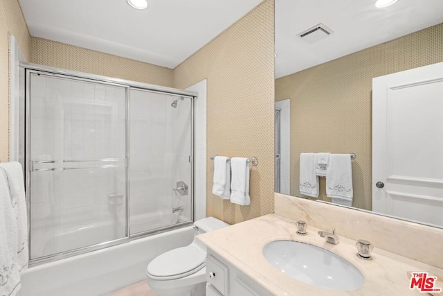 full bathroom featuring combined bath / shower with glass door, vanity, and toilet