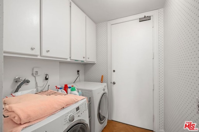 laundry area featuring cabinets, light parquet flooring, and separate washer and dryer