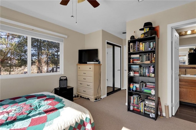 carpeted bedroom featuring a closet, ensuite bath, ceiling fan, and sink