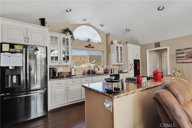 kitchen featuring appliances with stainless steel finishes, backsplash, stone counters, white cabinets, and lofted ceiling