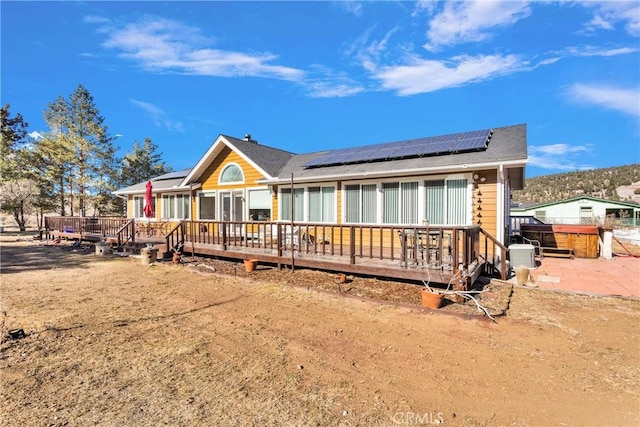 view of front of property featuring solar panels and a wooden deck