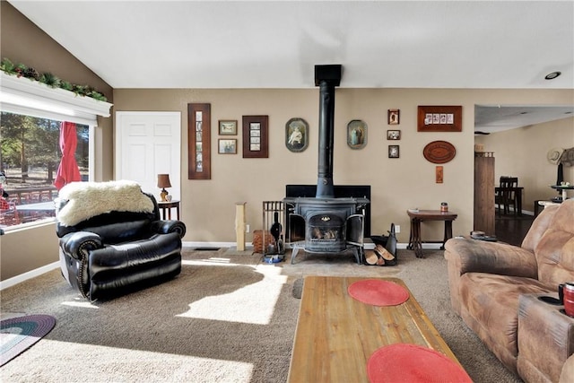 living room featuring carpet floors, a wood stove, and lofted ceiling