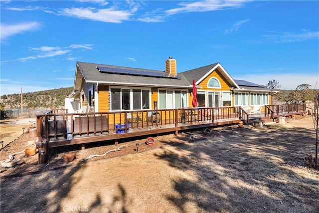 rear view of property with solar panels and a deck