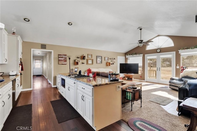 kitchen featuring dark hardwood / wood-style flooring, light stone counters, white cabinetry, and vaulted ceiling