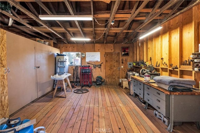 basement with a workshop area, hardwood / wood-style flooring, and wooden walls