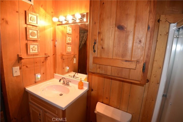 bathroom with vanity, toilet, and wooden walls